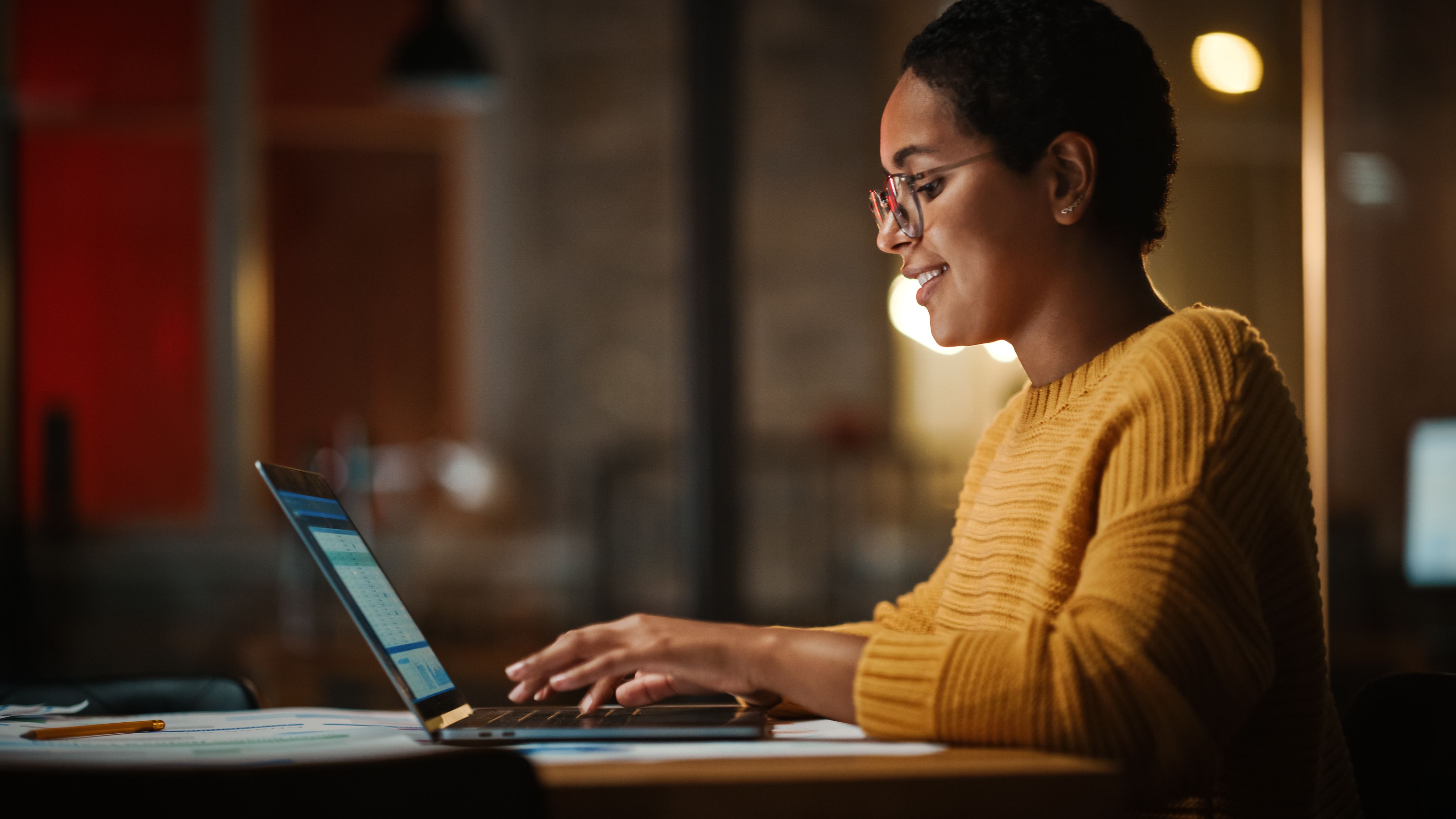 woman sitting in an office, working on a laptop